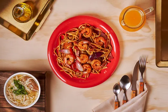 Tallarín saltado con camarones en plato rojo